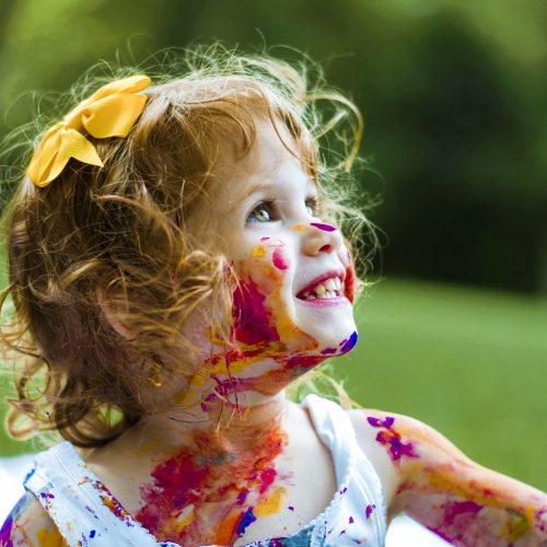 Fotografía infantil de una niña con la cara manchada de pintura en un parque